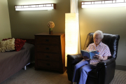 Resident in recliner reading in room.JPG