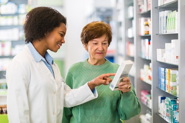 Senior woman buying medicine in the pharmacy while female African American pharmacist is assisting her